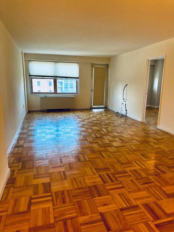 unfurnished living room featuring parquet flooring and radiator heating unit