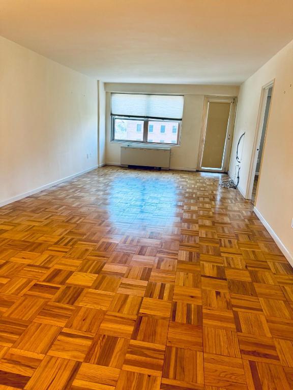 unfurnished room featuring radiator and light parquet floors