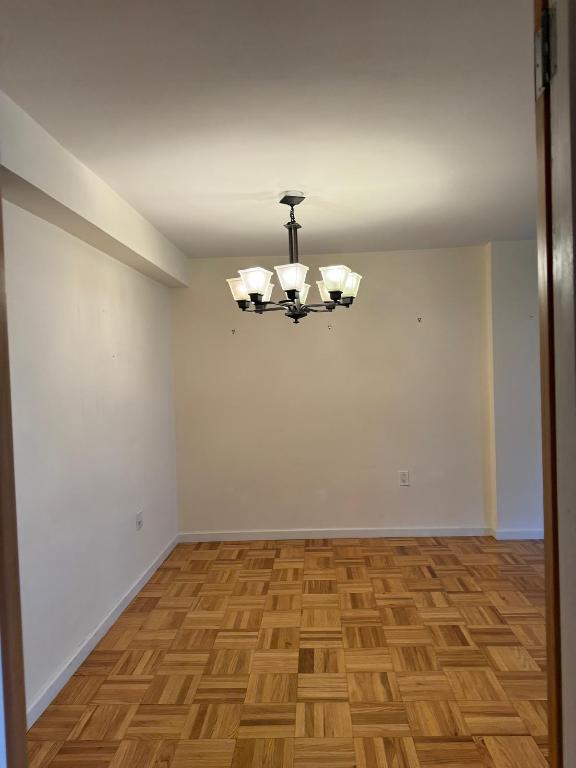 unfurnished room featuring an inviting chandelier and light parquet flooring