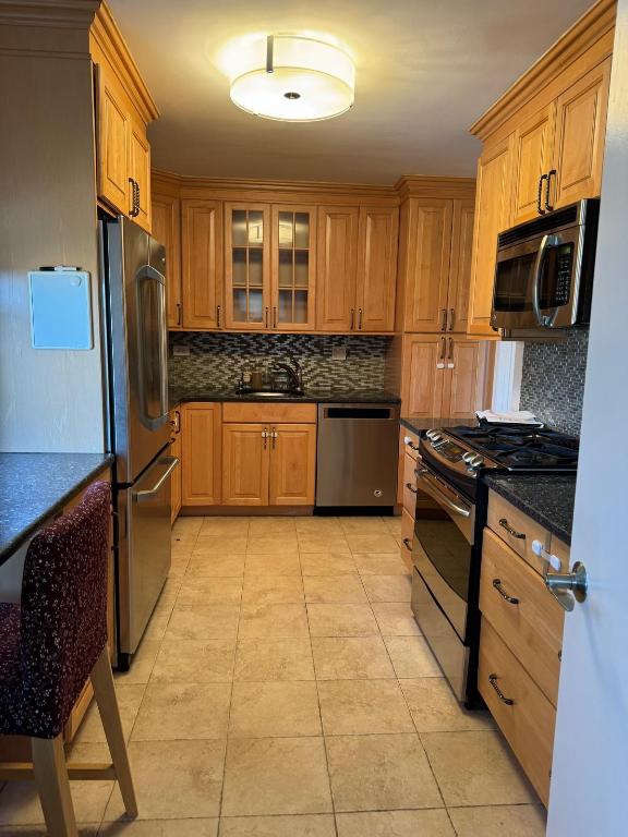 kitchen with sink, dark stone counters, light tile patterned floors, stainless steel appliances, and decorative backsplash