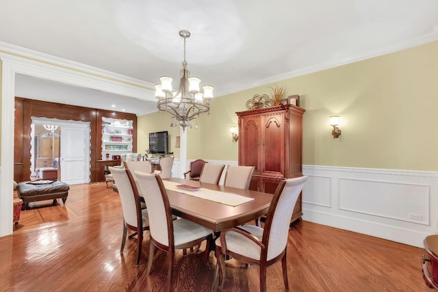 dining space with crown molding, wood-type flooring, and a notable chandelier