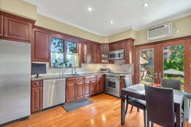 kitchen with appliances with stainless steel finishes, sink, ornamental molding, light stone counters, and french doors