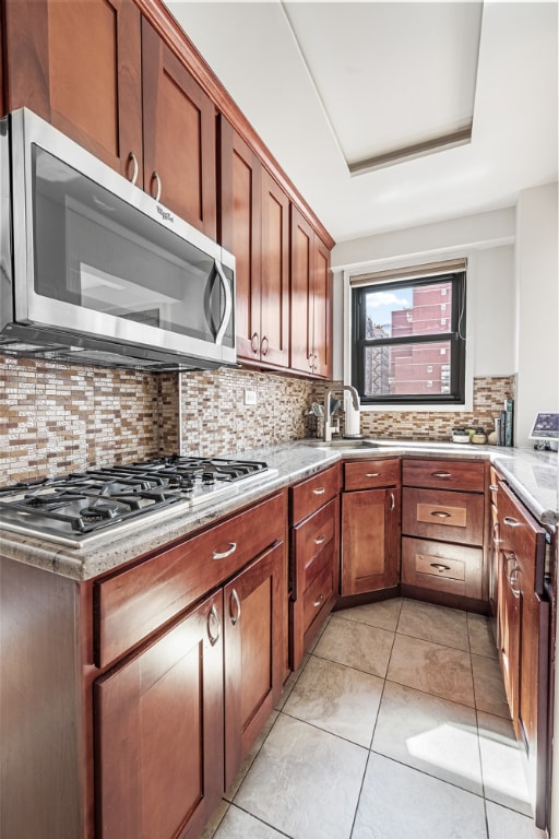 kitchen with stainless steel appliances, light tile patterned flooring, sink, and decorative backsplash