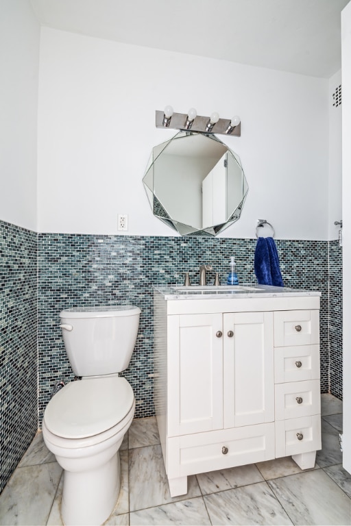 bathroom with vanity, tile walls, and toilet