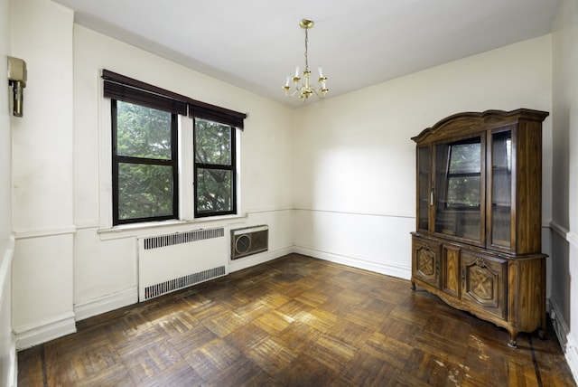 unfurnished dining area featuring an inviting chandelier, radiator heating unit, and dark parquet floors