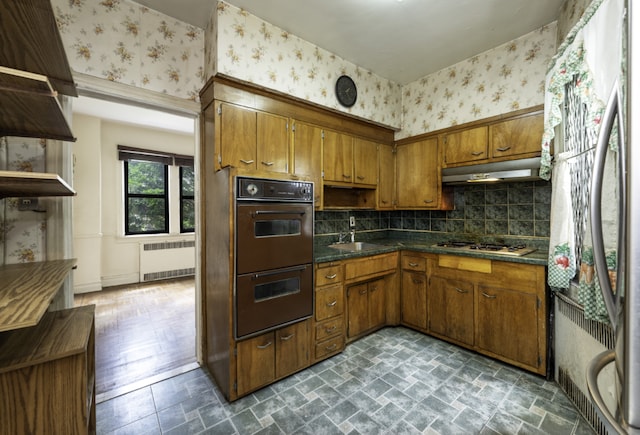 kitchen featuring tasteful backsplash, radiator, sink, and appliances with stainless steel finishes