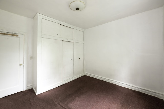 unfurnished bedroom featuring a closet and dark colored carpet