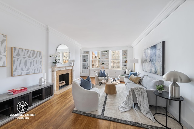 living area with baseboards, wood finished floors, a high end fireplace, and crown molding