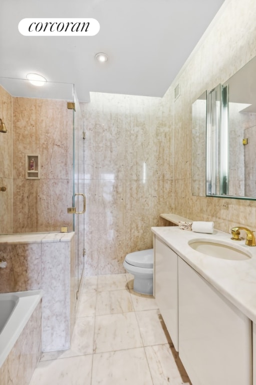 full bathroom featuring tile walls, vanity, shower with separate bathtub, and toilet