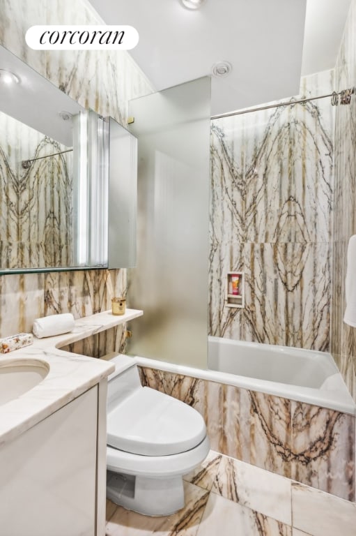 full bathroom with tiled shower / bath, vanity, and toilet