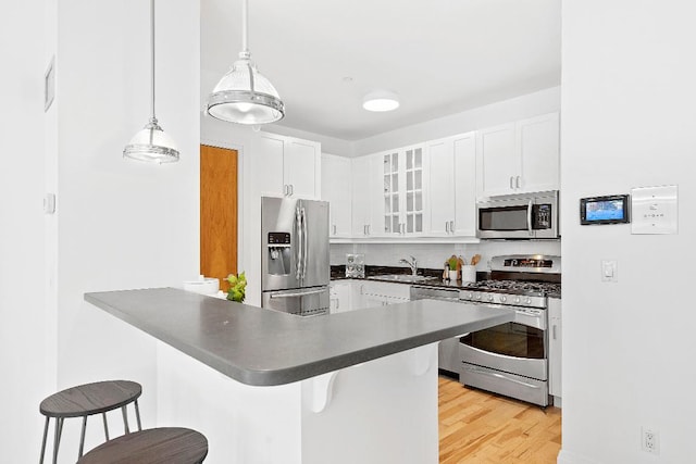 kitchen featuring pendant lighting, a breakfast bar, appliances with stainless steel finishes, white cabinetry, and kitchen peninsula