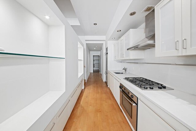 15 Broad St Unit 2206, New York City, NY 10005 - kitchen with stainless steel appliances, a sink, wall chimney exhaust hood, white cabinets, and light countertops
