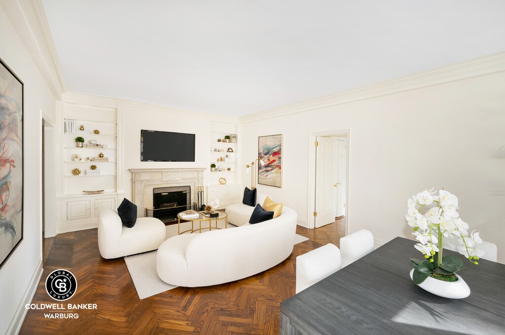 living room with built in shelves, crown molding, and a glass covered fireplace