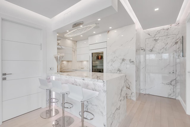 200 E 69th St Unit 31-A, New York City, NY 10021 - kitchen featuring white cabinets, modern cabinets, light stone countertops, a peninsula, and a breakfast bar