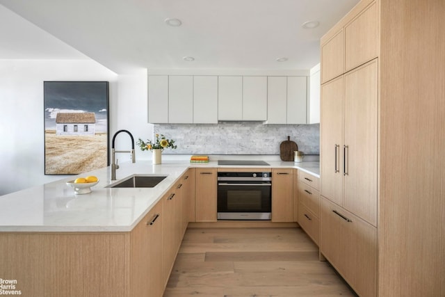 kitchen with sink, stainless steel oven, light brown cabinets, black electric cooktop, and decorative backsplash