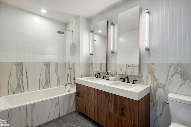 full bathroom featuring tiled shower / bath, tile walls, vanity, and toilet