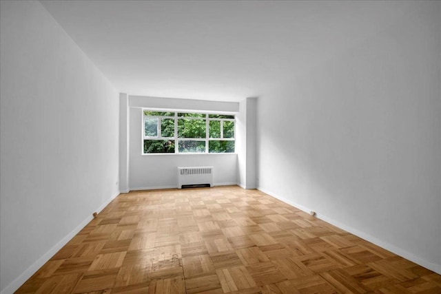 spare room featuring light parquet floors and radiator