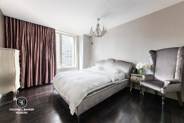 bedroom with dark hardwood / wood-style floors and a notable chandelier