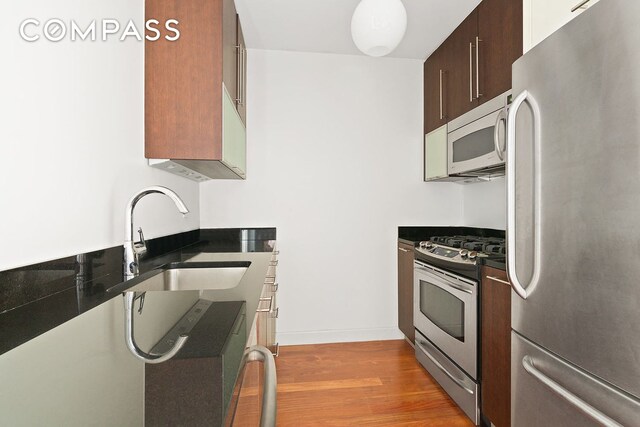 kitchen featuring light hardwood / wood-style floors, sink, appliances with stainless steel finishes, and dark brown cabinets