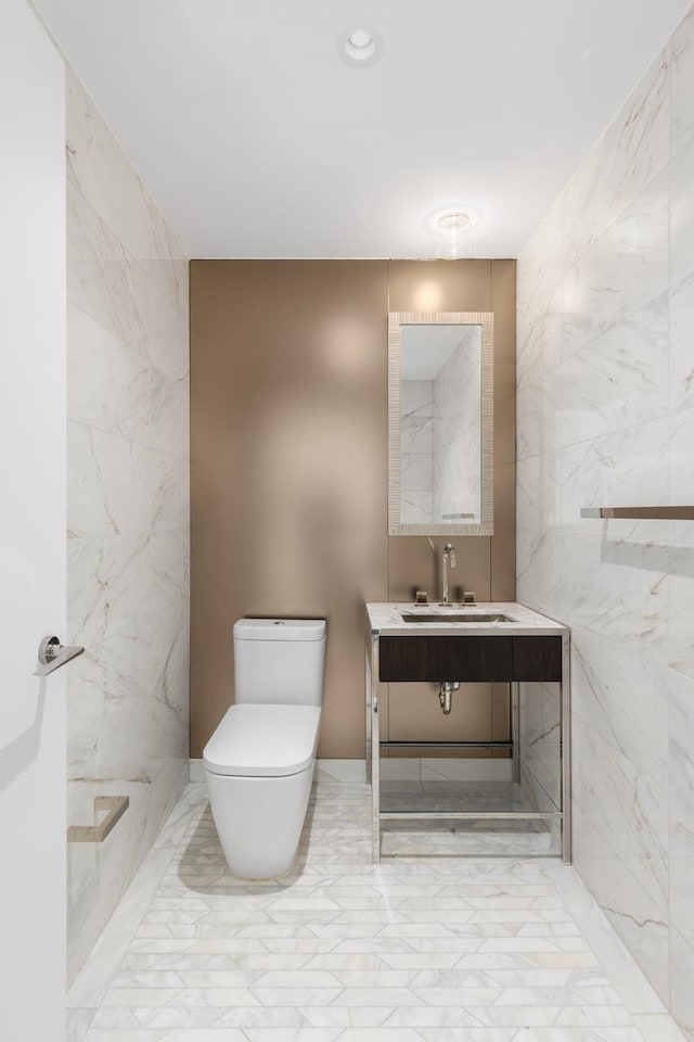 half bath featuring toilet, marble finish floor, and vanity