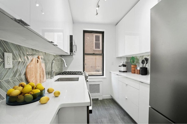 kitchen featuring sink, dark wood-type flooring, backsplash, stainless steel appliances, and white cabinets