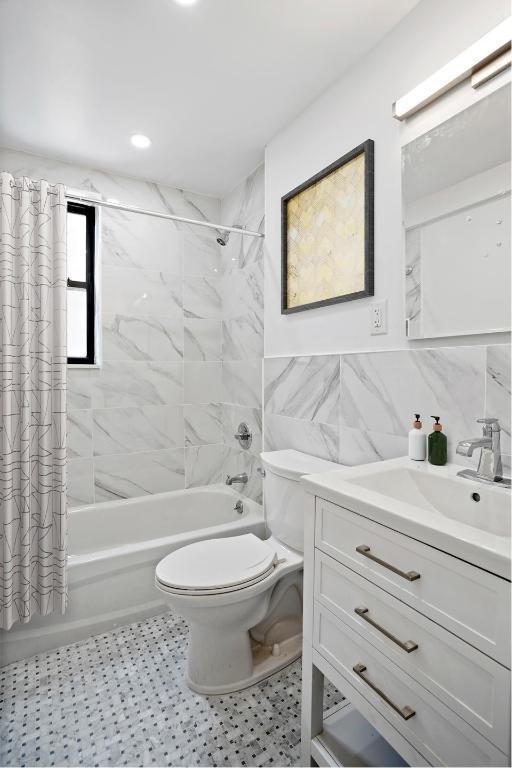 full bathroom with tile walls, vanity, toilet, and shower / bathtub combination with curtain