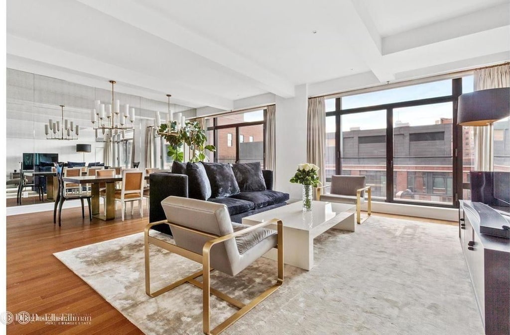 living room featuring a notable chandelier, beamed ceiling, and wood finished floors