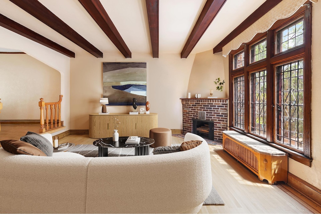 67-31 Ingram St, New York City, NY 11375 - living room with beamed ceiling, a brick fireplace, radiator heating unit, and light hardwood / wood-style flooring