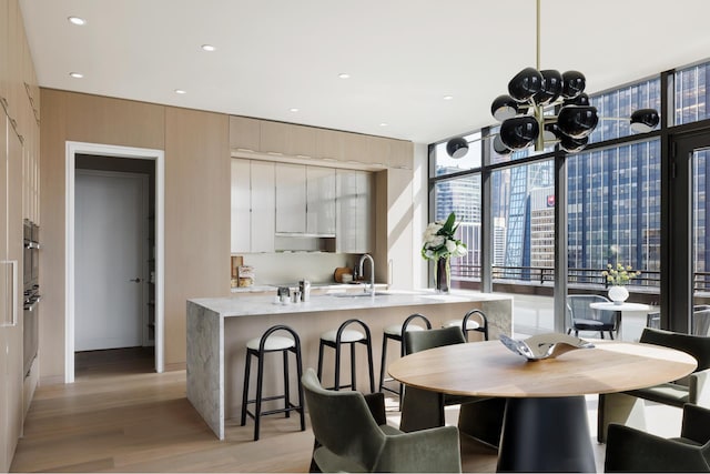 111 W 56th St Phc, Phc, New York City, NY 10019 - dining room featuring light wood-style flooring, recessed lighting, a notable chandelier, and expansive windows