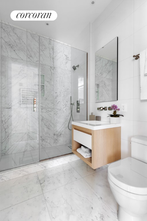 bathroom featuring toilet, tile walls, tiled shower, and vanity