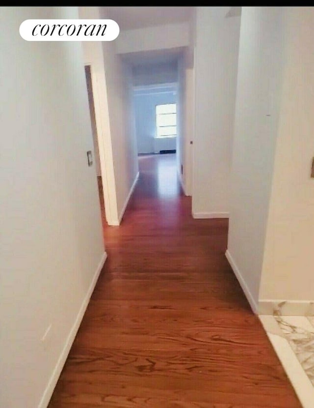 corridor featuring baseboards and wood finished floors