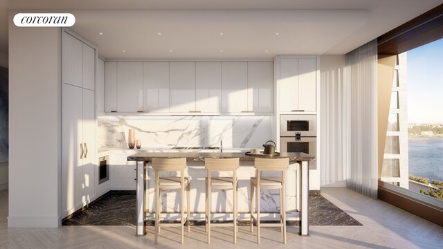 kitchen with a breakfast bar area, white cabinetry, backsplash, a center island, and oven