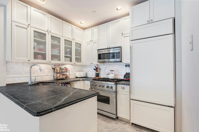 kitchen with white cabinets, premium appliances, kitchen peninsula, and sink