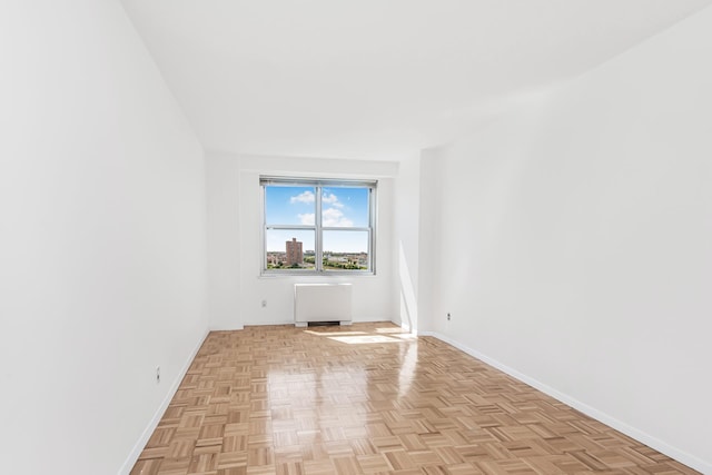 empty room featuring radiator and baseboards