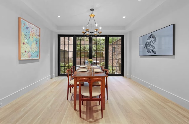 dining space with light wood-style floors, baseboards, and a tray ceiling