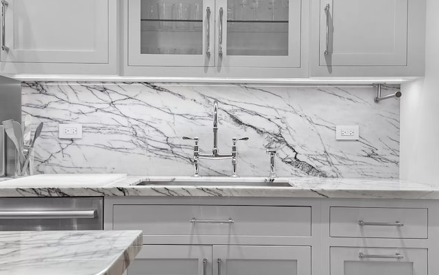 room details featuring dishwasher, decorative backsplash, and a sink