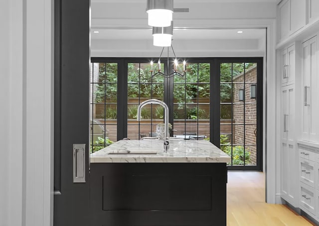 interior details featuring wood finished floors, a sink, and an inviting chandelier