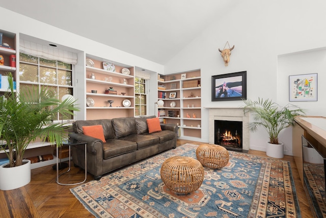 living area with vaulted ceiling, built in shelves, and a fireplace with flush hearth