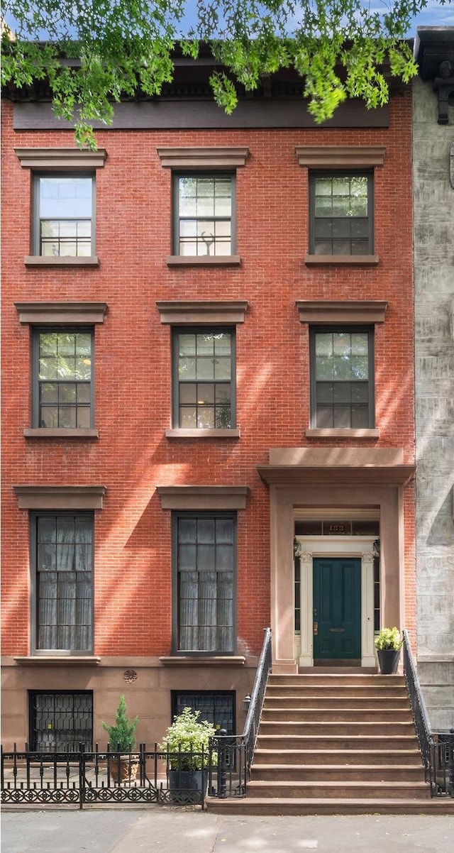 townhome / multi-family property featuring a fenced front yard and brick siding