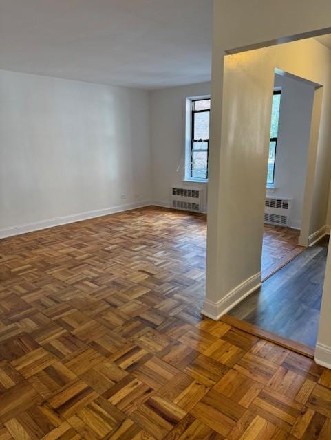 empty room with radiator and dark parquet floors