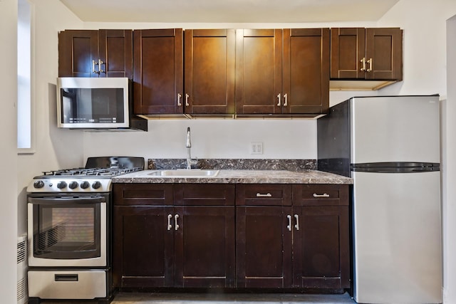 kitchen featuring appliances with stainless steel finishes, dark brown cabinets, and a sink