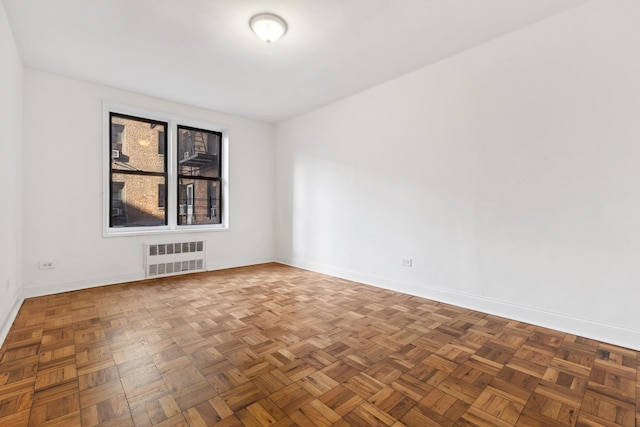 unfurnished room featuring baseboards and radiator