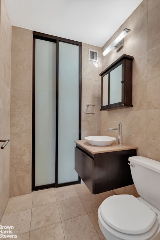 bathroom featuring toilet, vanity, tile walls, and tile patterned floors