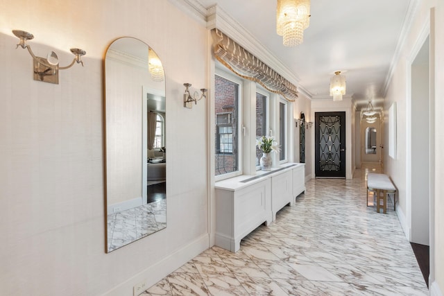 hallway featuring a chandelier, marble finish floor, baseboards, and ornamental molding