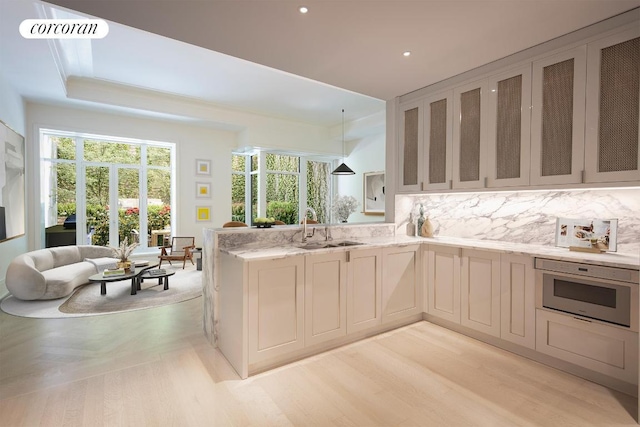 kitchen with sink, backsplash, a wealth of natural light, decorative light fixtures, and oven