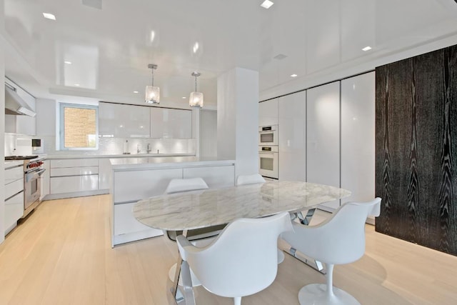 kitchen featuring tasteful backsplash, high end range, a center island, pendant lighting, and white cabinetry