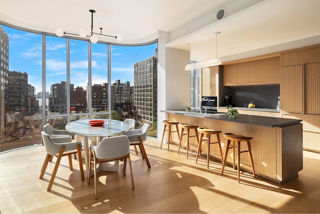 dining space with light wood-style floors, expansive windows, a city view, and visible vents