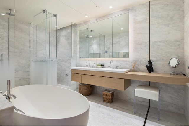 full bathroom with marble finish floor, a freestanding tub, and tile walls