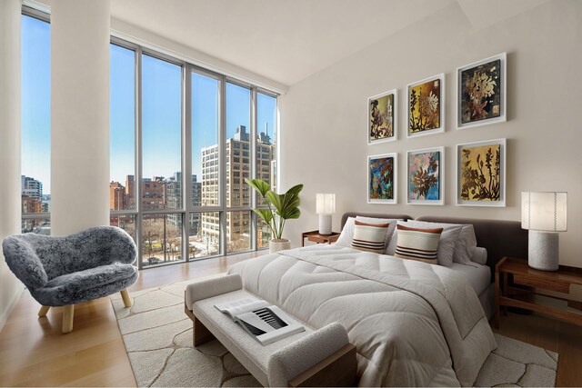 bedroom featuring a wall of windows, a city view, multiple windows, and wood finished floors