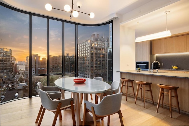 dining room featuring expansive windows, sink, light hardwood / wood-style floors, and a notable chandelier